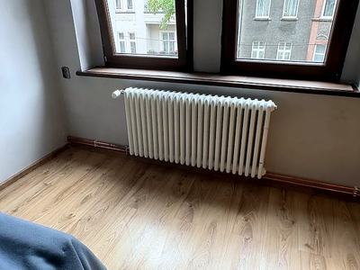 Grzejnik kolumnowy pod oknem z nową instalacją przy podłodze